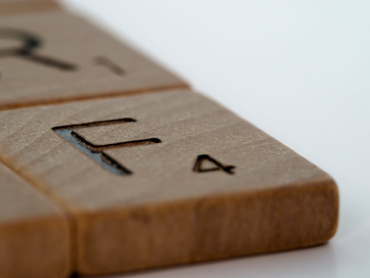 Macro shot of wooden Scrabble tiles with engraved letters and numbers.